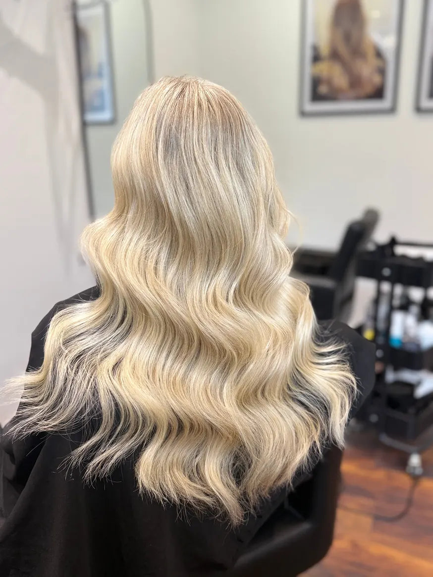 Lange blonde bølger med mørkere bund set bagfra.